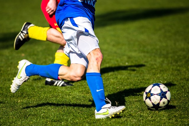 Sporttherapie Fussball Zwei Spieler verfolgen einen Fußball
